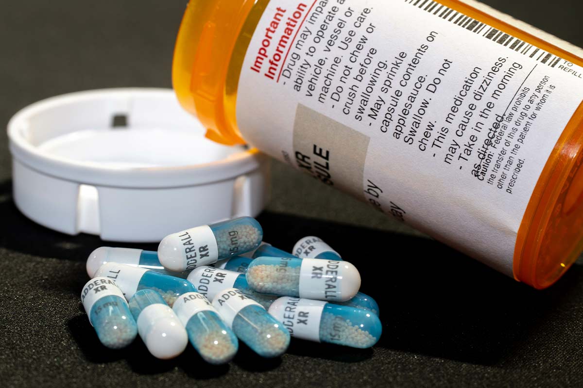 adderall capsule spilling out of a pill bottle - how long does adderall stay in your system