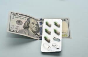 A hundred-dollar bill beside prescription pills, symbolizing the cost and integration of medication-assisted treatment (MAT) in outpatient addiction care.