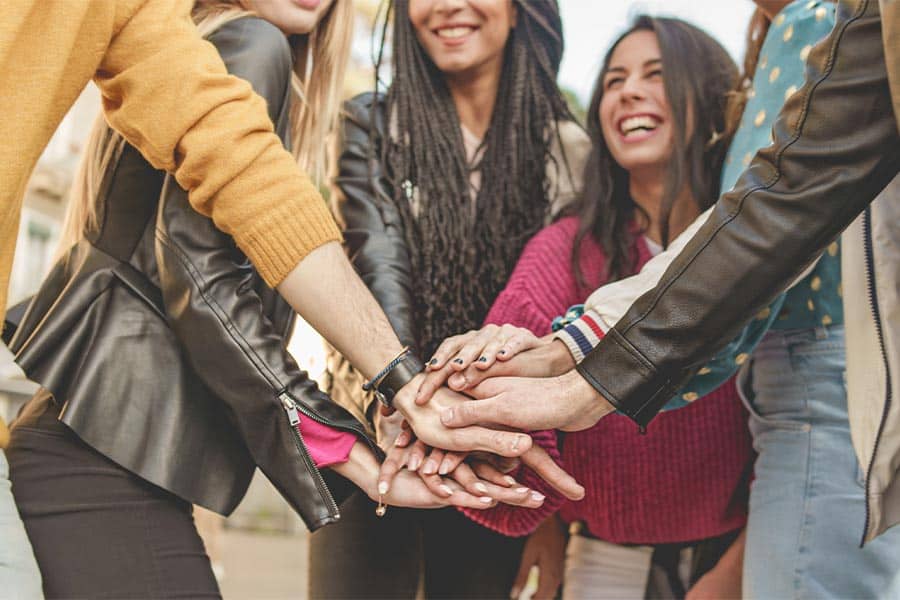happy group of people joing hands outside after ketamine therapy for depression