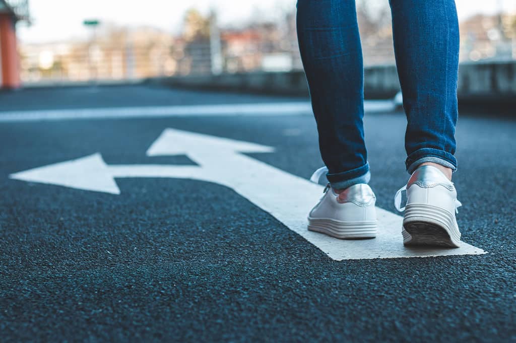 Person pausing on a path symbolizing awareness of triggers in addiction recovery