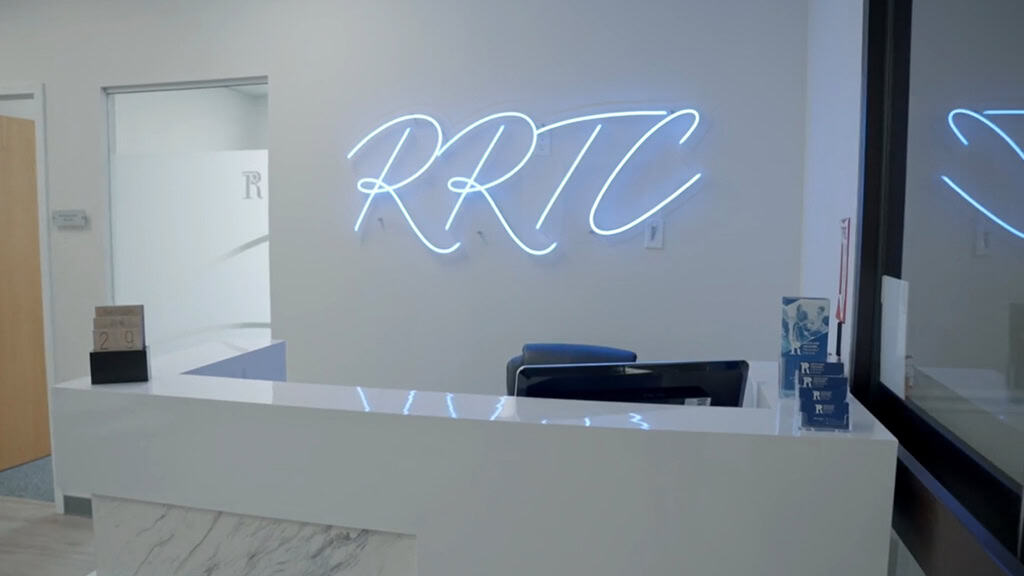 Reception desk with neon RRTC sign at Rockland Recovery's alcohol rehab center in Massachusetts
