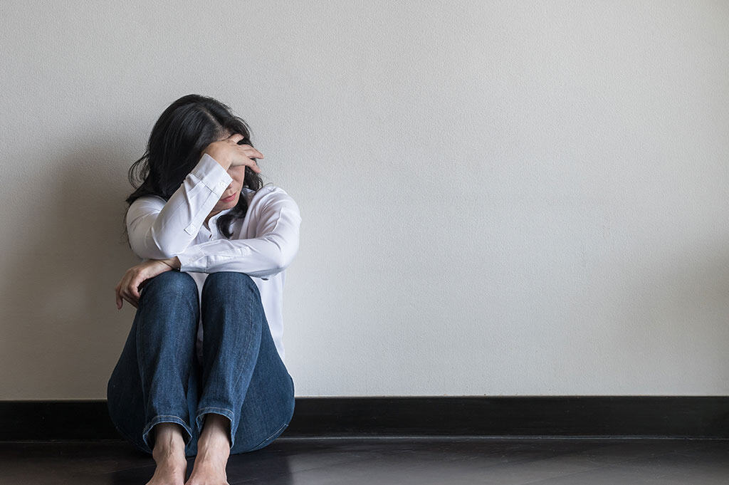 woman in distress sitting on the floor wondering how long does suboxone stay in your system